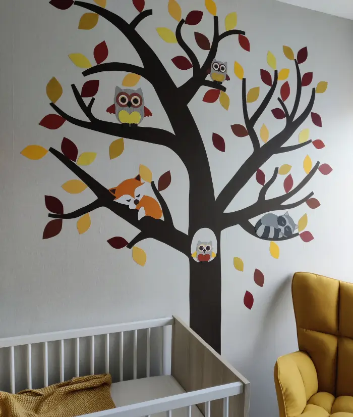 Okergele babykamer met een behangboom als muurdecoratie